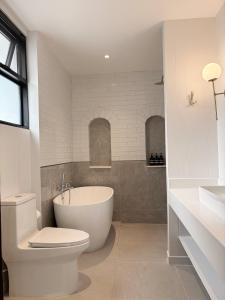 a bathroom with a tub and a toilet and a sink at Pennkiat House in Bangkok