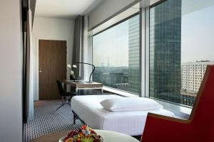 a hotel room with a bed and a desk and a window at Meliá Paris La Défense in Courbevoie