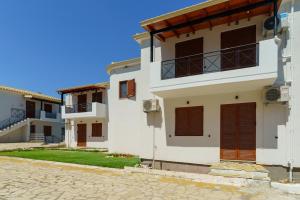 a white house with brown shutters on a street at The Dandy Family Apartments in Syvota