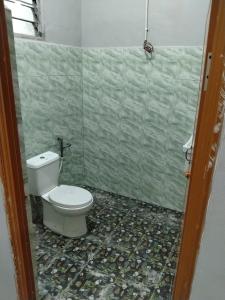 a bathroom with a toilet and a tiled floor at Roomstay Ust Omar in Tumpat