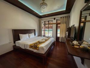 a bedroom with a large bed and a television at Namkhan Riverside Hotel in Luang Prabang +53 photos