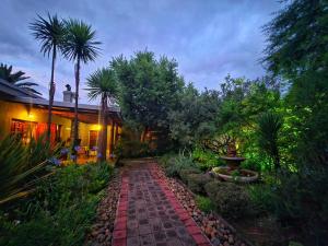 a brick walkway in front of a house with palm trees at Aqua Terra Guest House in Lydenburg