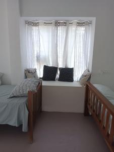 a bedroom with two beds and a window with curtains at Casa De Campo in Idukki