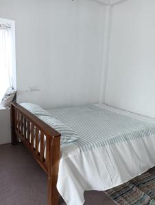 a bed in a white room with a wooden frame at Casa De Campo in Idukki +4 photos