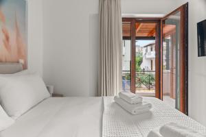 a bedroom with a white bed with two towels on it at The Dandy Family Apartments in Syvota