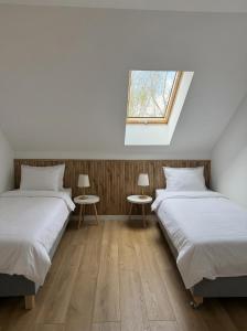 two beds in a room with two tables and a window at Sielski Dom in Suwałki