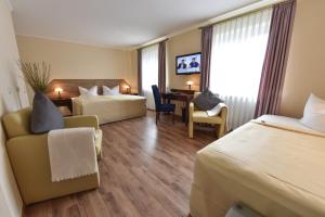 a hotel room with two beds and a desk at Atrium Hotel Amadeus in Osterfeld