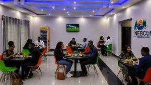a group of people sitting at tables in a restaurant at NEBCON Executive Lodge in Kitwe