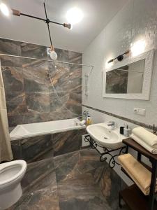 a bathroom with a sink and a tub and a toilet at Apartament Birutes 22 in Klaipėda +10 photos