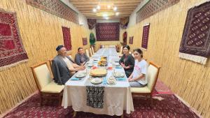 a group of people sitting at a long table at TURKMAN's PALACE in Urganch