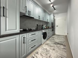 a kitchen with white cabinets and a washer and dryer at Bucovina Comfort Apartament in Gura Humorului