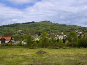 a town on a hill with a field and houses at Bucovina Comfort Apartament in Gura Humorului