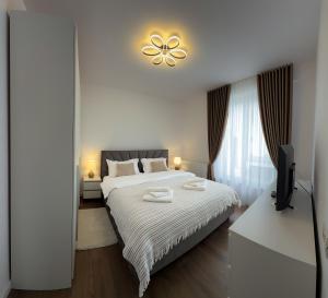 a bedroom with a white bed and a television at Bucovina Comfort Apartament in Gura Humorului