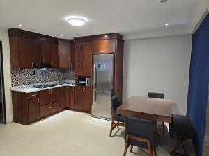 a kitchen with wooden cabinets and a table and a refrigerator at Apartment with separate parking in Heroica Nogales