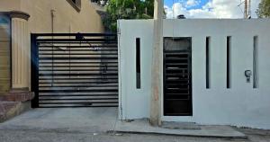 a white fence with a door next to a building at Apartment with separate parking in Heroica Nogales