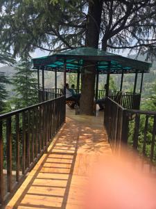 a wooden walkway with a green canopy on a tree at Bhaderwah Resorts Pvt Ltd in Dranga