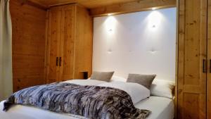 a bedroom with a large white bed with wooden walls at Chalet Tannheimer Tal in Zöblen