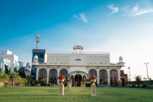 a large white building with flower pots in front of it at HOTEL DHAROHAR in Pura Raghunāth
