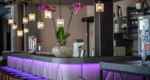 a bar with a vase with flowers in it at PLAZA INN Salzburg Messe in Salzburg