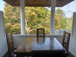 a dining room table with two chairs and a large window at Peacock Forest Villa in Kosgoda +15 photos