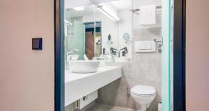 a bathroom with a white sink and a toilet at PLAZA INN Salzburg Messe in Salzburg