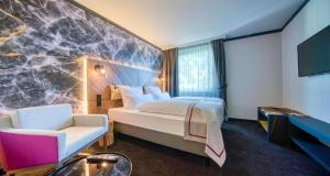 a hotel room with a bed and a couch and a tv at PLAZA INN Salzburg Messe in Salzburg