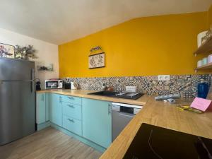 a kitchen with blue cabinets and a yellow wall at The globe trotter - Perpignan in Perpignan