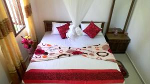 a bedroom with a bed with red and white sheets at Kavi Villa in Bentota