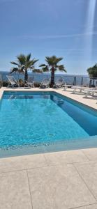 a blue swimming pool with palm trees and the ocean at Dinary Deluxe Apartments in Vir