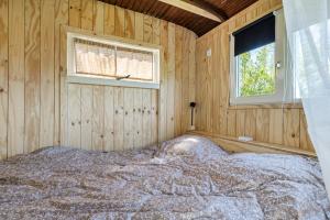 a bed in a wooden room with a window at Camping de Wartenster - De Pipowagen in Wartena