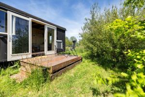 a wooden deck with a chair on the side of a house at Camping de Wartenster - De Pipowagen in Wartena