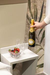a person opening a bottle of wine next to a bowl of strawberries at Hotel Giardinetto Al Sant'Orsola in Bologna