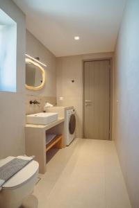 a bathroom with a toilet and a sink and a washing machine at 5 Elements - Agapi's Houses in Antiparos