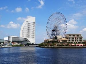 a ferris wheel in a city with buildings and water at 大津屋a in Yokohama