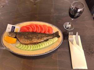 a plate of fish and vegetables and a glass of wine at Hotel Kristal in Dospat