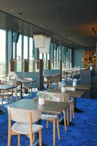 a dining room with tables and chairs and windows at Snow Hotel Druskininkai in Druskininkai