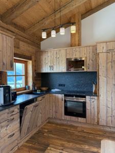a kitchen with wooden cabinets and black counter tops at Almhütte Eibingalm in Saalbach-Hinterglemm