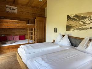 two beds in a room with wooden walls at Almhütte Eibingalm in Saalbach-Hinterglemm