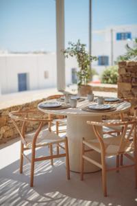 a table and chairs with plates and bowls on it at 5 Elements - Agapi's Houses in Antiparos +155 photos