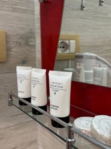 a shelf with four white moisturizers in front of a mirror at The White Villa - Guest House in Bogovë