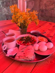 a red table with a plate of food on a table at Rob Guest House in Garni