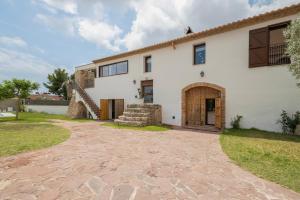 an exterior view of a white house with a stone driveway at Villa de Lujo Cerca de Sitges in Sant Pere de Ribes