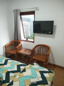 a living room with two chairs and a flat screen tv at Dalem Suwarno Baru in Timuran
