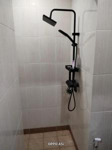 a shower with a shower head in a bathroom at Dalem Suwarno Baru in Timuran