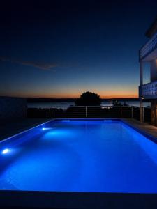 a large blue swimming pool at night with a building at Apartments Ana in Gornji Karin