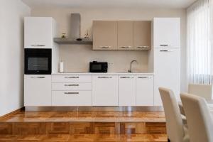 a white kitchen with white cabinets and a wooden floor at Apartments Ana in Gornji Karin