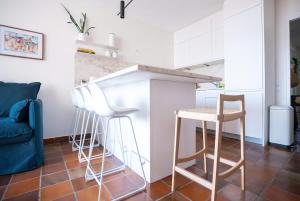a kitchen with white cabinets and stools in a room at La bulle canetoise - vue mer in Canet-en-Roussillon +29 photos