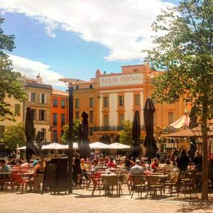a group of tables and chairs with umbrellas in front of a building at Le Balcon Catalan - Perpignan Centre in Perpignan