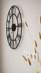 a black clock hanging on a wall next to some wheat at K-49 prie Jūros in Klaipėda