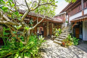 a building with stairs and a tree in front of it at Griya Gribig Guest House Mitra RedDoorz in Malang